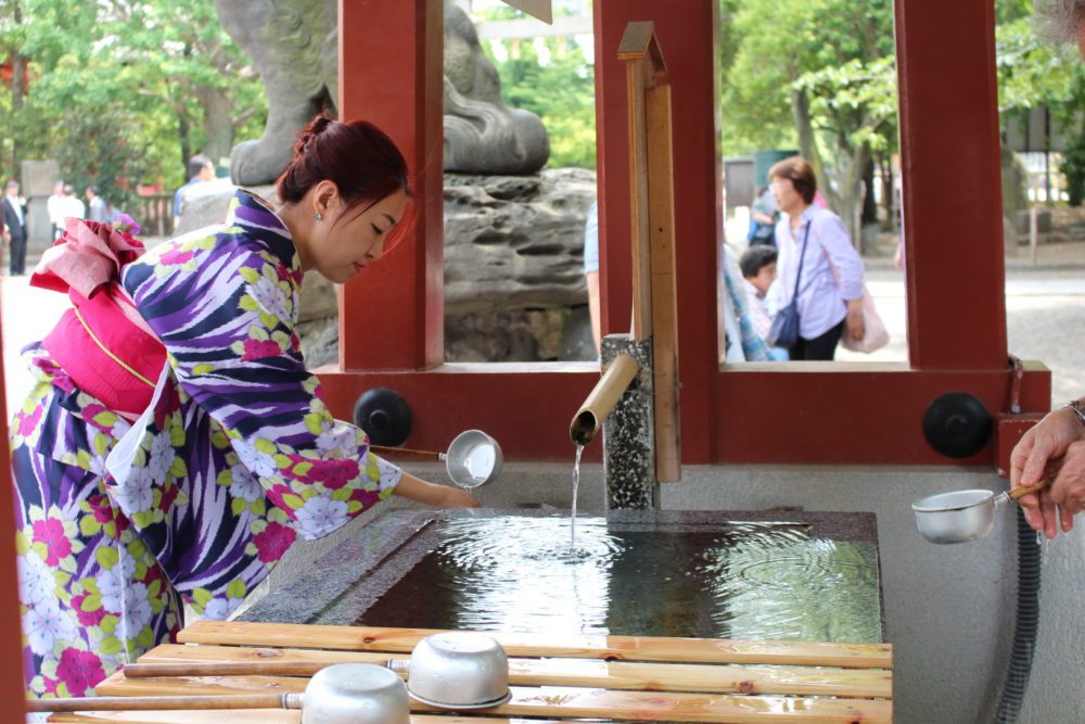 Frau in Kimono an einem Trinkbrunnen in Tokyo